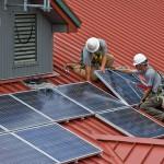 A photo of an installer putting up solar panels on a stable block in West Sussex, UK