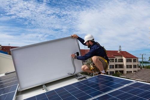 a photo of a solar panel installer on a roof